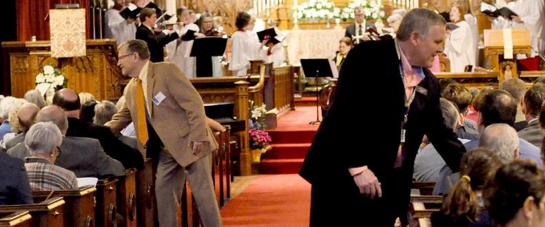 Men interact with seated parishoners