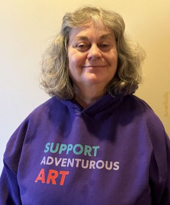 A photo of Nanette wearing a purple hoodie that says "Support adventurous art"